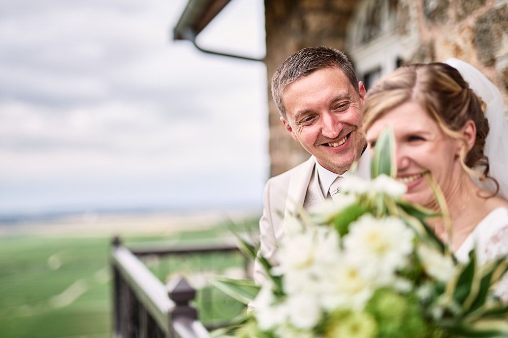 Florian sourit derrière Audrey et son bouquet sur la terrasse
