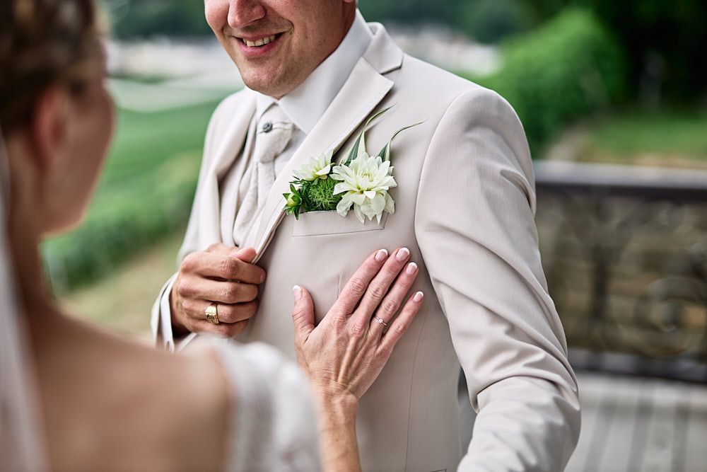 Main d’Audrey posée sur la veste de Florian et sa boutonnière