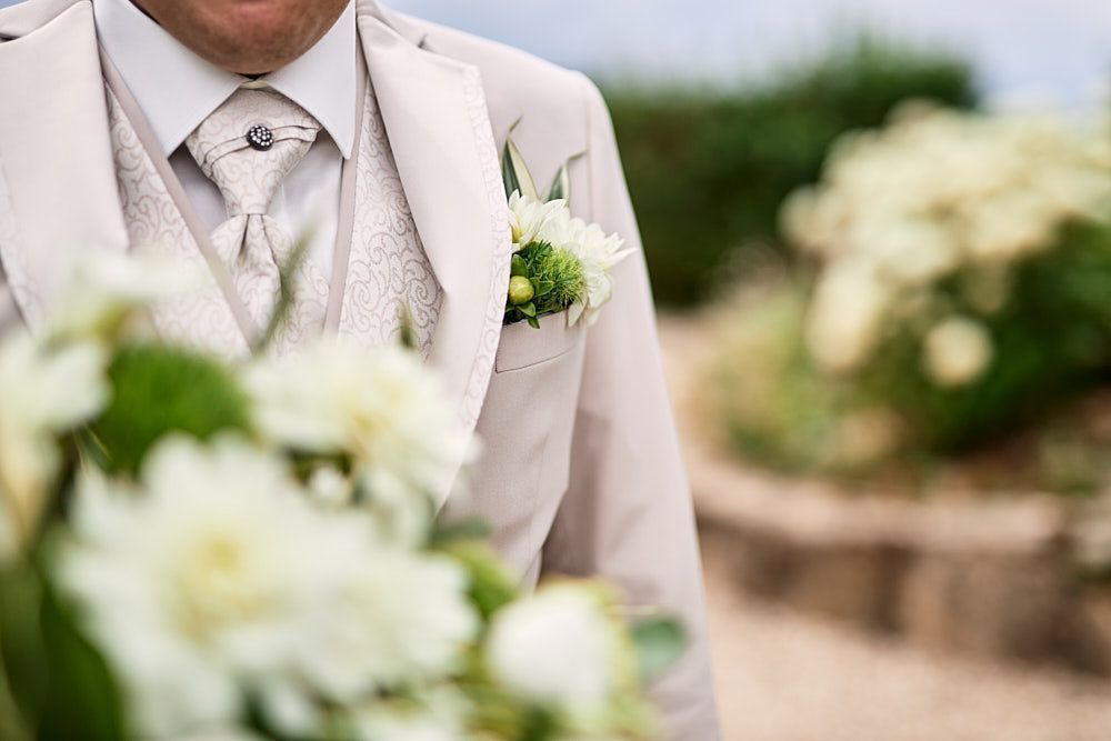 Détails de la tenue du marié avec sa boutonnière florale