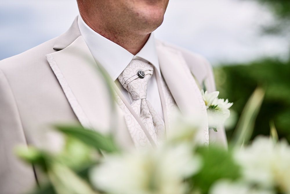 Détail de la boutonnière du marié photographiée à travers les fleurs