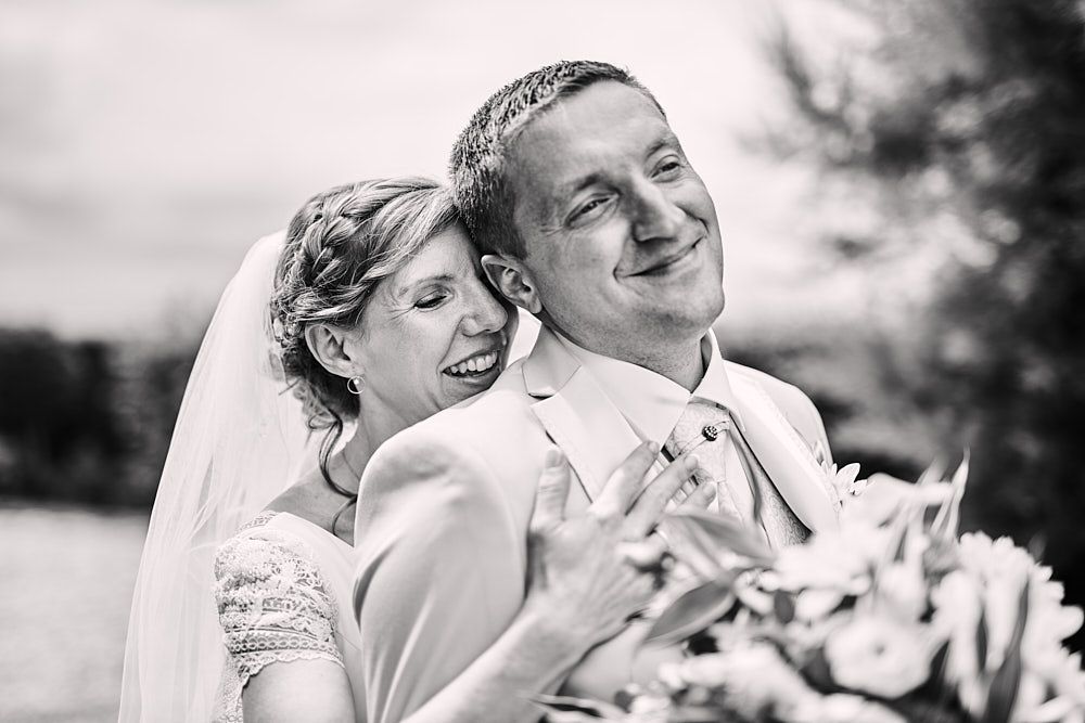 Audrey enlace Florian par-derrière pendant leur first-look en noir et blanc