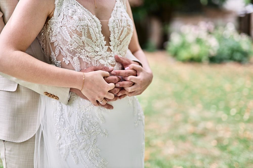 Mains d’Harmonie et Anthony posées sur la robe de la mariée