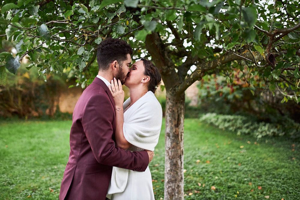 Julie et Guilhem s’embrassent sous un arbre au Clos de la Robe