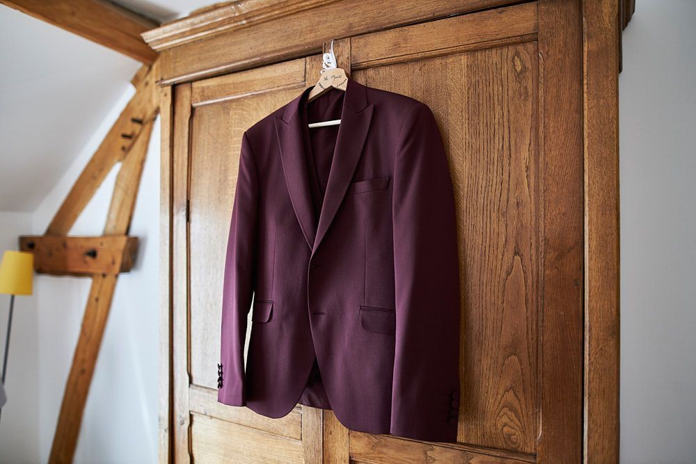 Costume bordeaux de Guilhem suspendu dans la chambre